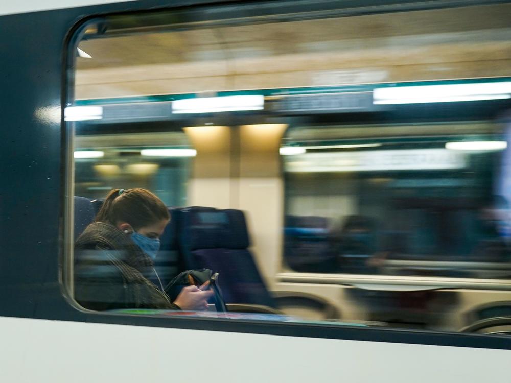A commuter wearing a protective face mask looks at her mobile phone in a train arriving at the Central Train Station in Brussels in May 2020. Belgium's new rule addresses the ever-blurry line between work and personal life in the pandemic.