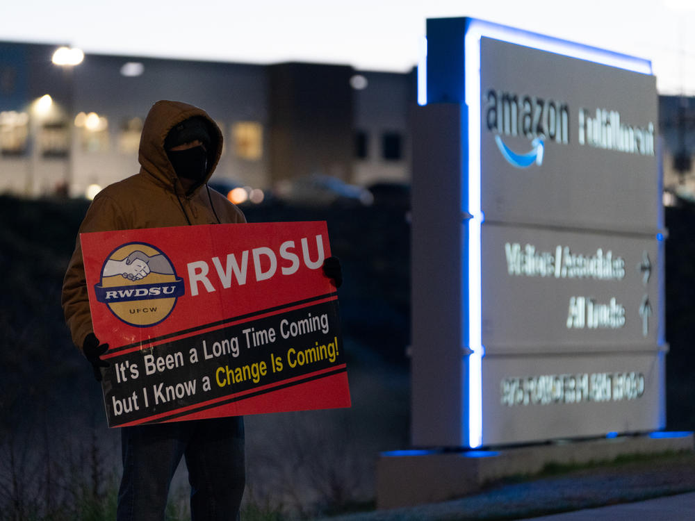 A retail union representative holds a sign by the Amazon warehouse in Bessemer, Ala., during the first union election in March 2021.