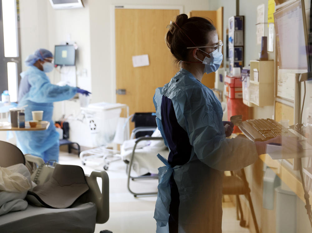 Nurse Elisa Gilbert checks on a patient in the acute care COVID-19 unit at Harborview Medical Center in Seattle on Jan. 21. The highly transmissible omicron variant of the coronavirus is putting a significant strain on health systems nationally, resulting in staffing shortages and changes in capacity strategies.