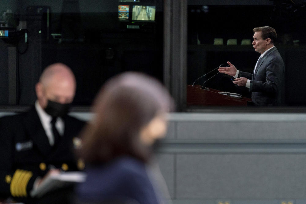 Pentagon spokesman John Kirby, seen in reflection, speaks during a briefing at the Pentagon in Washington on Feb. 2. President Joe Biden is sending about 2,000 troops from Fort Bragg, N.C., to Poland and Germany this week and sending part of an infantry Stryker squadron of roughly 1,000 troops based in Germany to Romania.