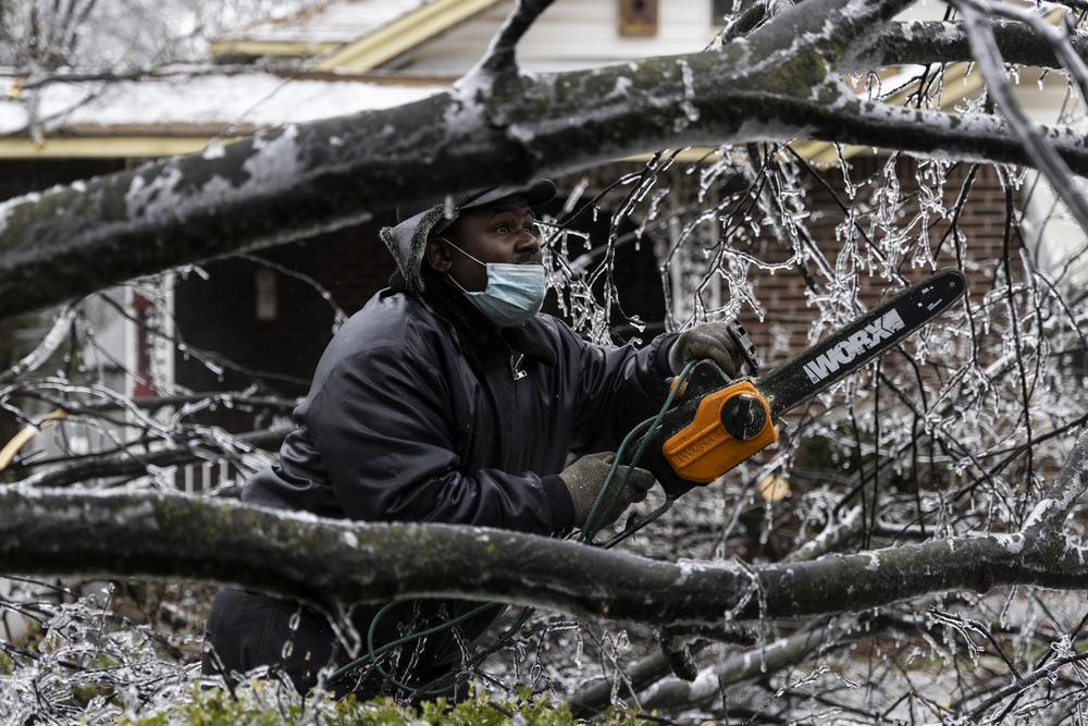 Edward Caldwell works to clear a downed tree at his mother's house on Thursday in Memphis, Tenn.
