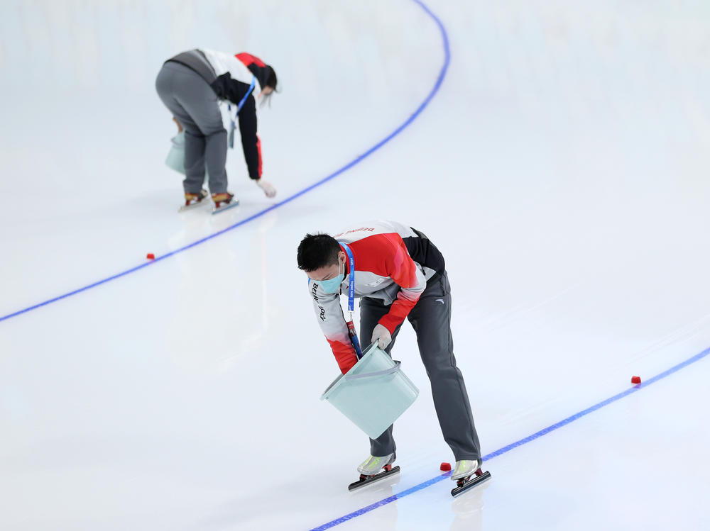 Track staff place lane markers on the ice before the first speedskating event of the Beijing 2022 Winter Olympic Games.