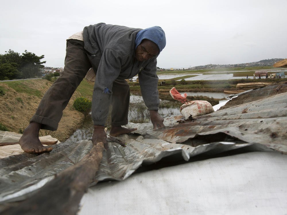A man secures his home during adverse weather, in Antananarivo, Madagascar, Feb. 5, 2022. After gaining strength in the Indian Ocean with gale-force winds reaching peaks of 145 miles per hour, a cyclone made landfall roughly 500 kilometers (310 miles) east of the capital city on Saturday.