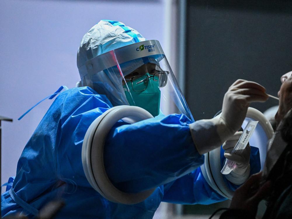 A health worker collects swab samples to test for COVID-19 from a participant of the Beijing 2022 Olympic Games.