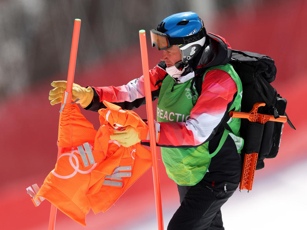 A courseworker removes a gate flag following the postponement of the men's downhill due to high winds on day two of the Beijing 2022 Winter Olympic Games at National Alpine Ski Center.