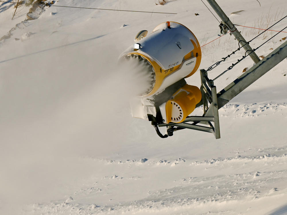 A snow machine spreads artificial snow at the National Alpine Skiing Center at the 2022 Winter Olympics.
