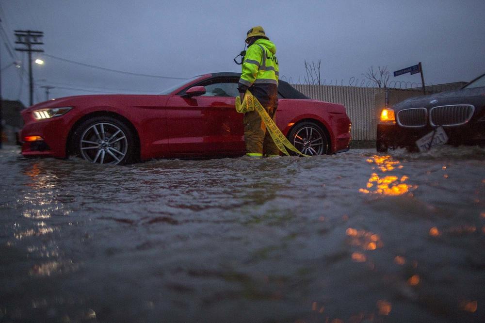 A firefighter checks on stalled cars on a flooded street in Sun Valley, Calif., during a 2017 storm. When rainfall overwhelms stormwater systems, flooding can happen far from a river or creek.