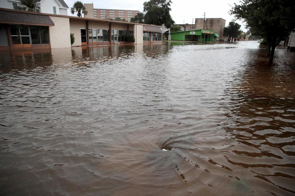 Water drains on a street flooded by rain from Hurricane Harvey in 2017 in Galveston, Texas. After getting new rainfall data, some Texas cities are building infrastructure to handle more water.