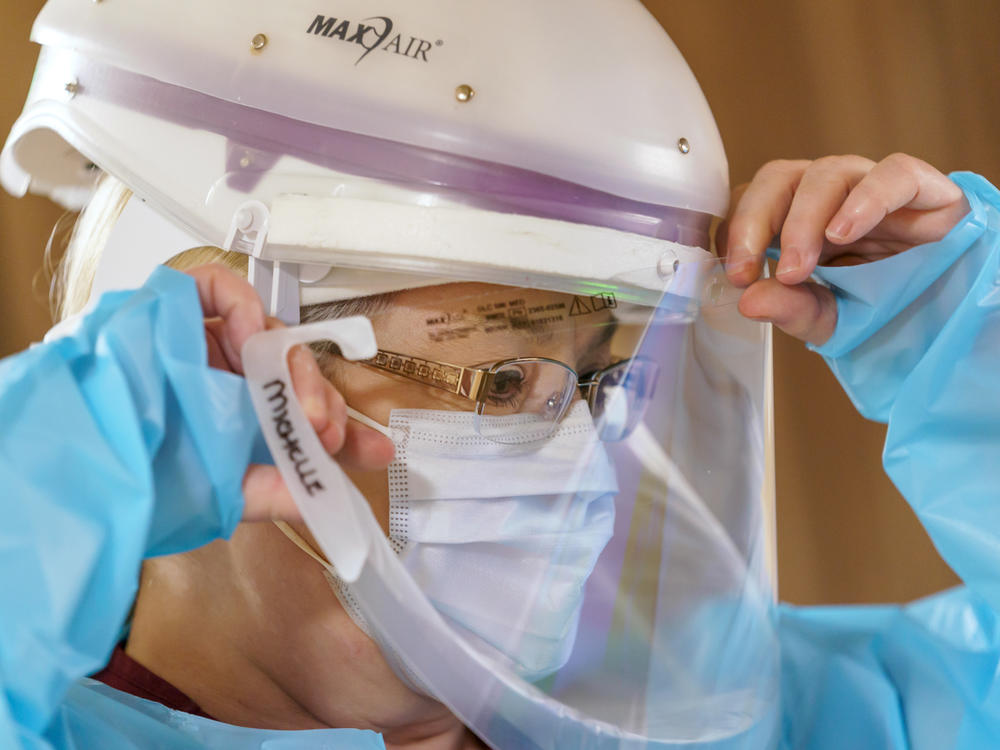 Nursing assistant Michelle Bryan dons a protective face shield before entering the room of a COVID-19 patient on the acute care floor.