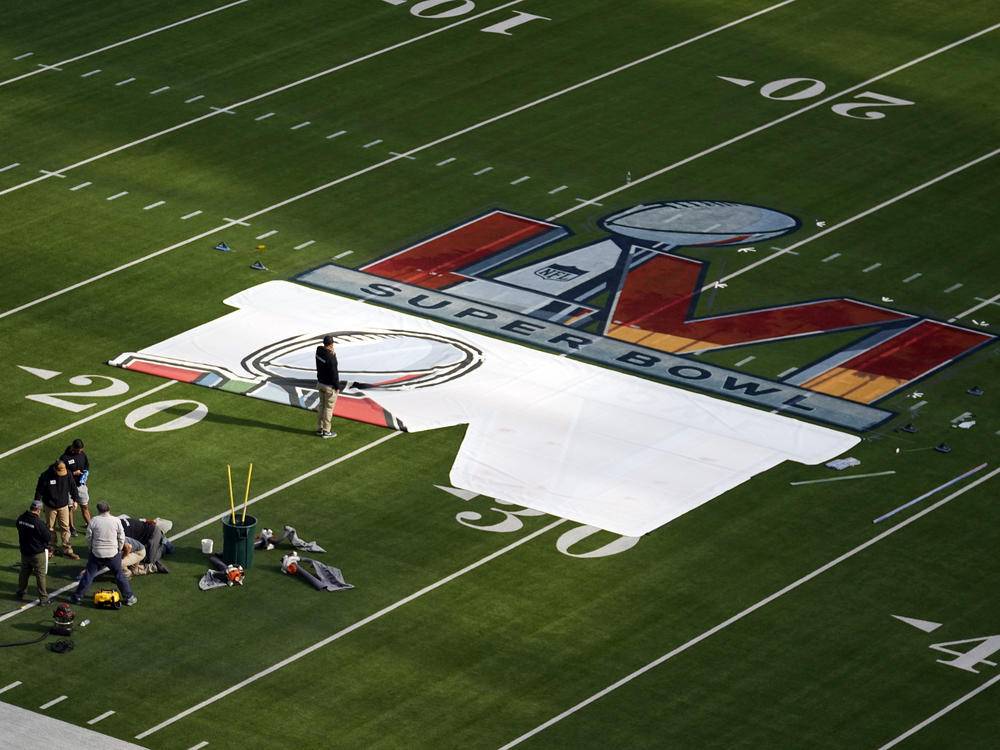 Workers paint a logo on the field at SoFi Stadium on Feb. 8.