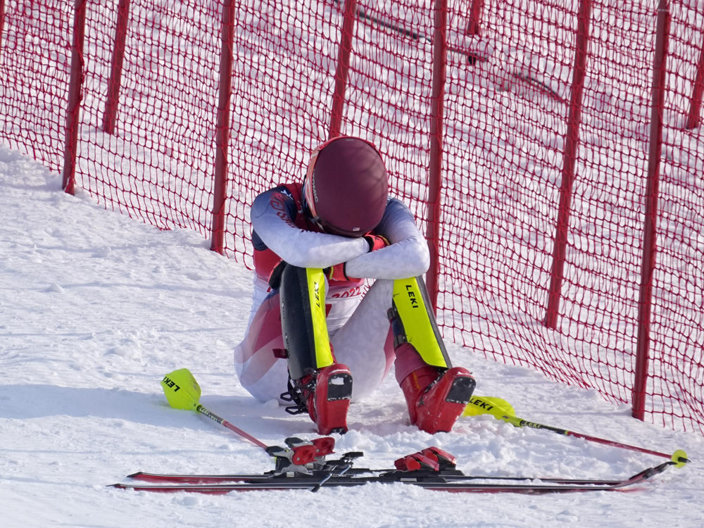 Shiffrin sits on the side of the course after skiing out in the first run of the women's slalom at the 2022 Winter Olympics.