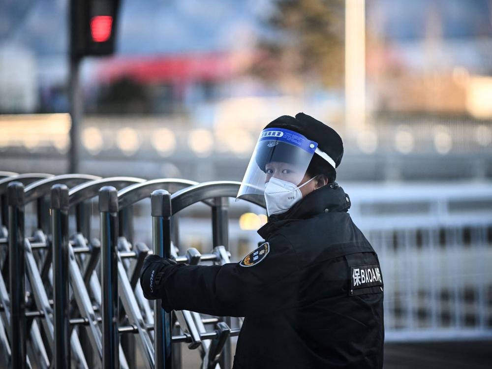 A security personnel opens a barrier at a checkpoint on a road within the closed-loop bubble in Beijing that was set up for the Olympic Games.