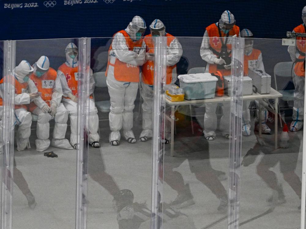 Medical personnel wearing personal protective equipment keep watch during a hockey game at the Beijing 2022 Winter Olympic Games.