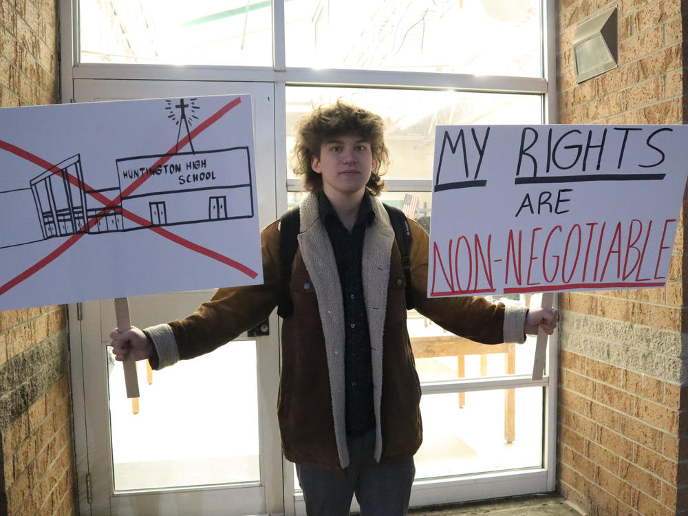 Huntington High School senior Max Nibert holds signs he planned to use during a walkout students were to stage at Huntington High School in Huntington, W. Va., on Wednesday. The protest followed an evangelistic Christian revival assembly last week that some students at Huntington High were mandated by teachers to attend.