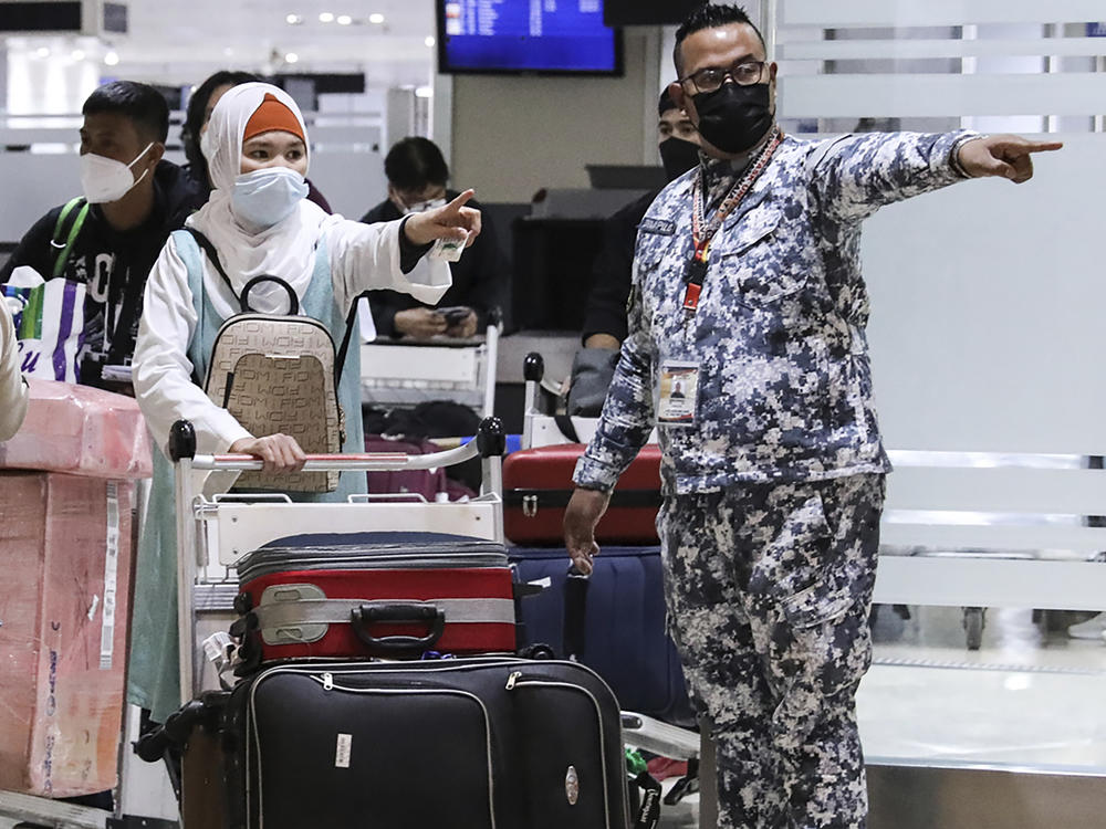 Members of the Philippine Coast Guard assist passengers as they arrive at Manila's International Airport. The Philippines lifted a nearly 2-year ban on foreign travelers Thursday as an omicron-fueled surge eases.