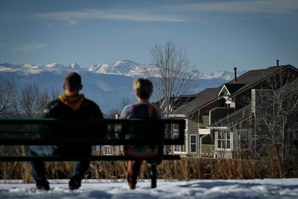 Dos personas se sientan en primer plano mientras las Montañas Rocosas de Colorado se elevan a la distancia en Westminster, Colorado, el 29 de enero.