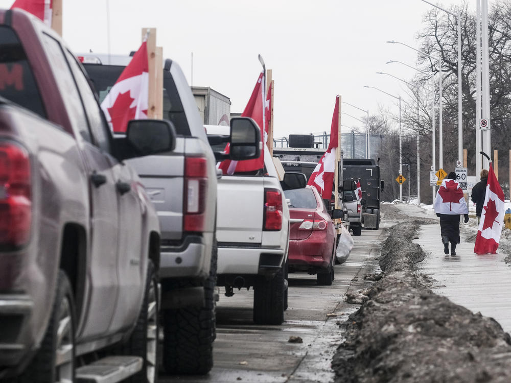 Protesters with trucks and other vehicles adorned in signs and Canadian flags gather near Ambassador Bridge on February 9 in Windsor, Canada. The bridge is the busiest land border crossing in North America in terms of trade volume.