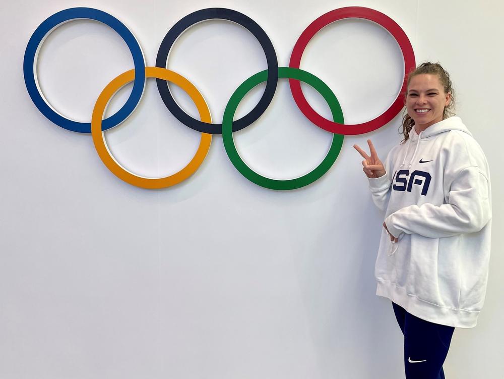 Kelly Curtis stands next to the Olympic rings. She's competing in the skeleton competition at the Beijing Olympics.