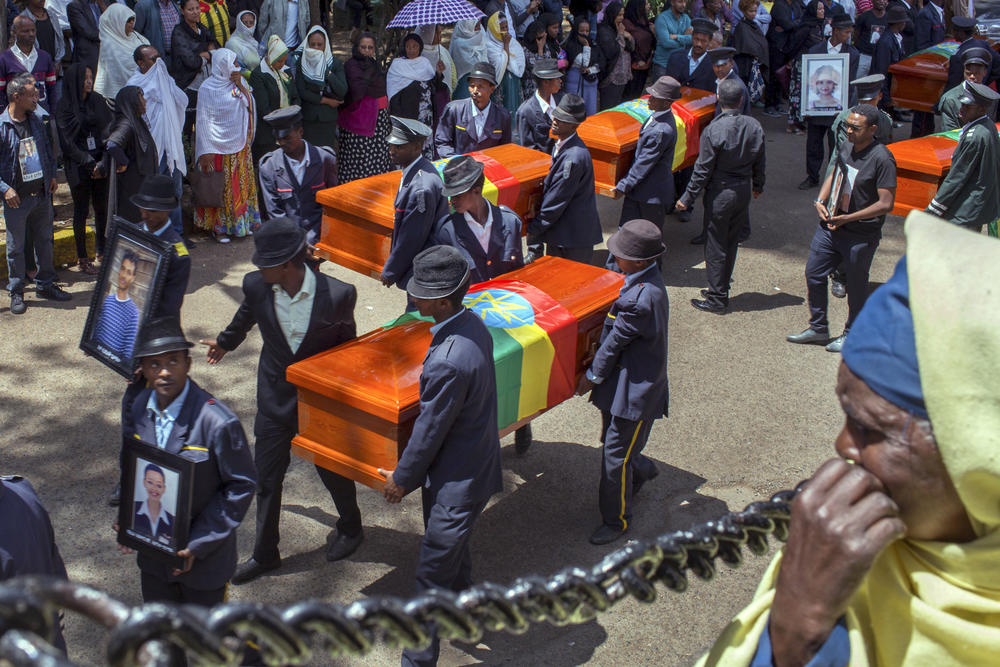 Relatives grieve next to empty caskets draped with the national flag at a mass funeral at the Holy Trinity Cathedral in Addis Ababa, Ethiopia Sunday, March 17, 2019.