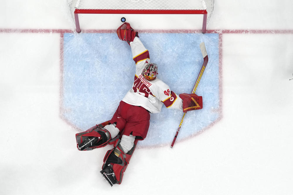 China goalkeeper Jieruimi Shimisi (Jeremy Smith) (45) reaches for a goal by United States' Brian Oneill during a preliminary round men's hockey game at the 2022 Winter Olympics, Thursday, Feb. 10, 2022, in Beijing.