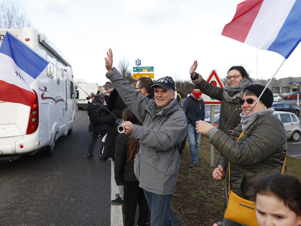 People wave to a convoy departing for Paris on Friday in Strasbourg. Authorities in France and Belgium have banned road blockades threatened by groups inspired by protesters in Canada.