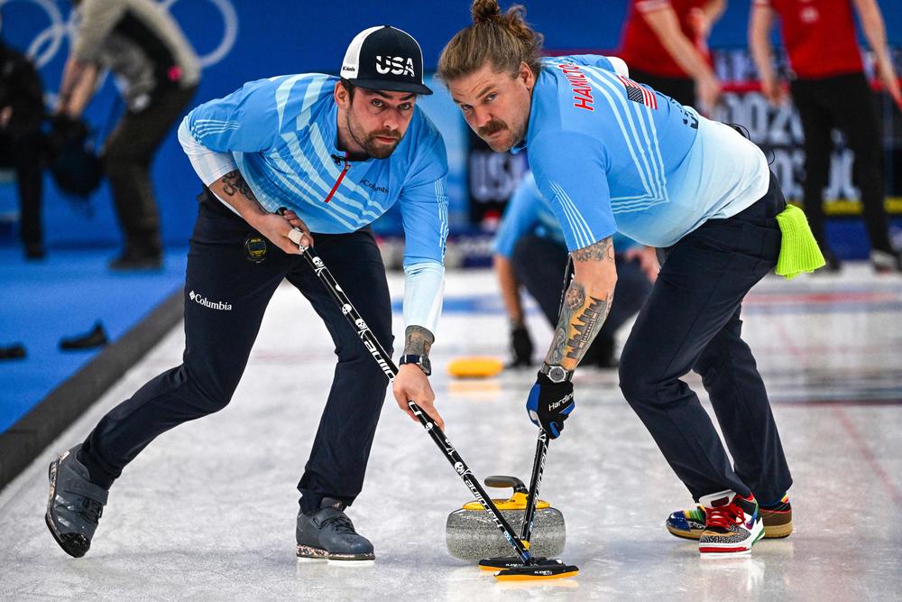 USA's Christopher Plys (L) and Matt Hamilton sweep during the men's round robin session 3 game of the Beijing 2022 Winter Olympic Games curling competition between Britain and USA at the National Aquatics Centre in Beijing on February 11, 2022.