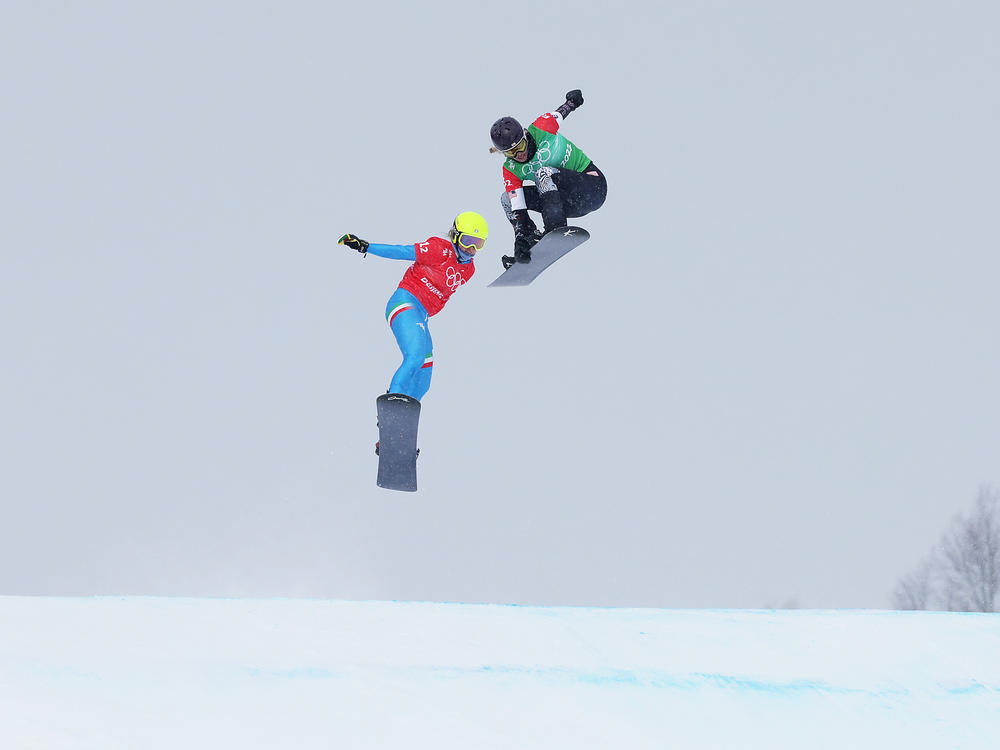 Lindsey Jacobellis (right) and Italy's Michela Moioli (left) compete during the first-ever mixed team snowboard cross event at the Beijing 2022 Winter Olympics.