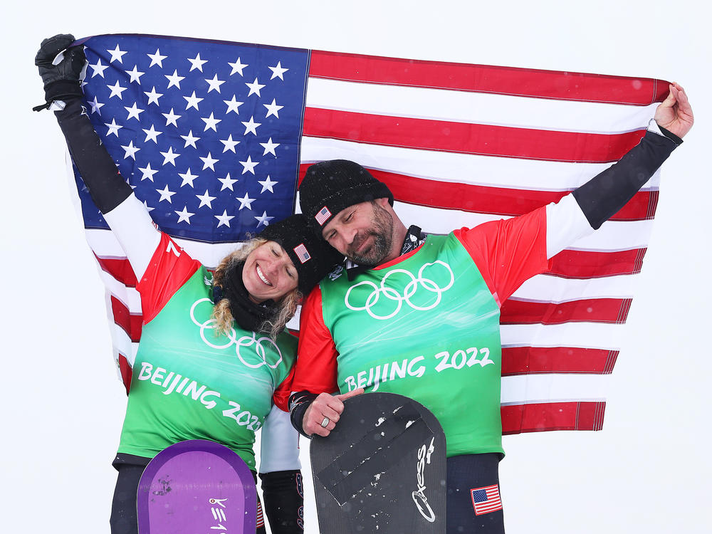 Gold medalists Lindsey Jacobellis (left) and Nick Baumgartner celebrate their win of the mixed team snowboard cross finals at the flower ceremony during the Beijing 2022 Winter Olympics on Feb. 12, 2022.