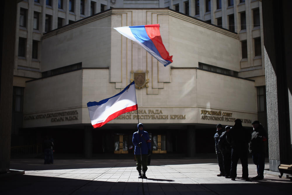 A man holds a Crimean flag in front of the Crimean parliament building on March 17, 2014, in Simferopol, Ukraine. People in Crimea overwhelmingly voted to secede from Ukraine during a referendum vote on March 16 and the Crimean Parliament declared Independence and formally asked Russia to annex them.
