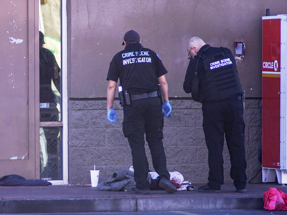 Albuquerque Police crime scene specialists photograph bloody articles of clothing after multiple people were stabbed on Sunday.