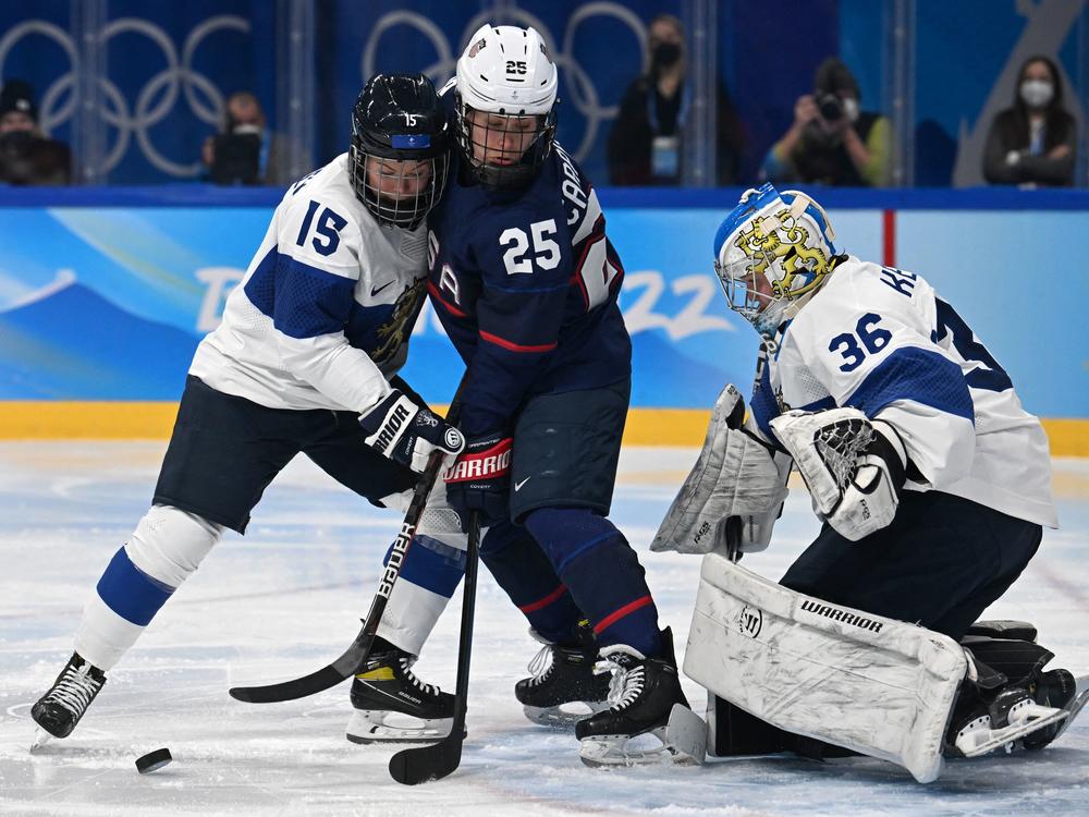 Finland's Minnamari Tuominen (left) and Team USA's Alexandra Carpenter vie for the puck next to Finland's goaltender Anni Keisala during the women's ice hockey semi-final match of the Beijing 2022 Winter Olympic Games.