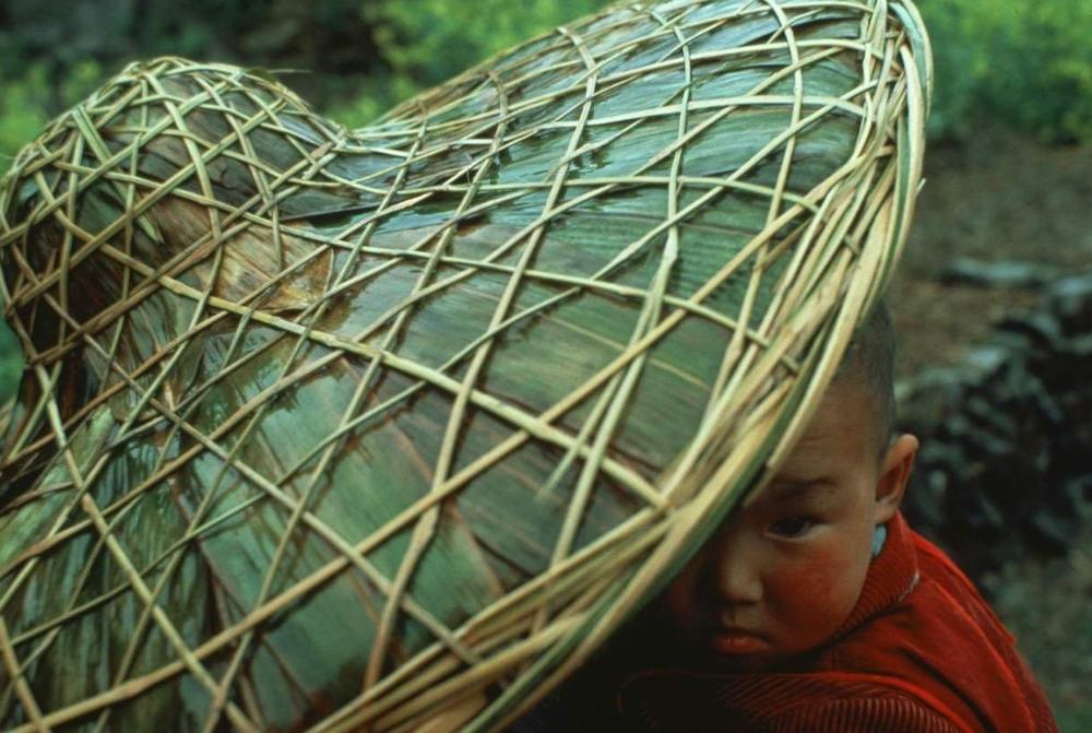 In Anhui Province, China, a child peeks from under his mother's traditional hat, 1981.