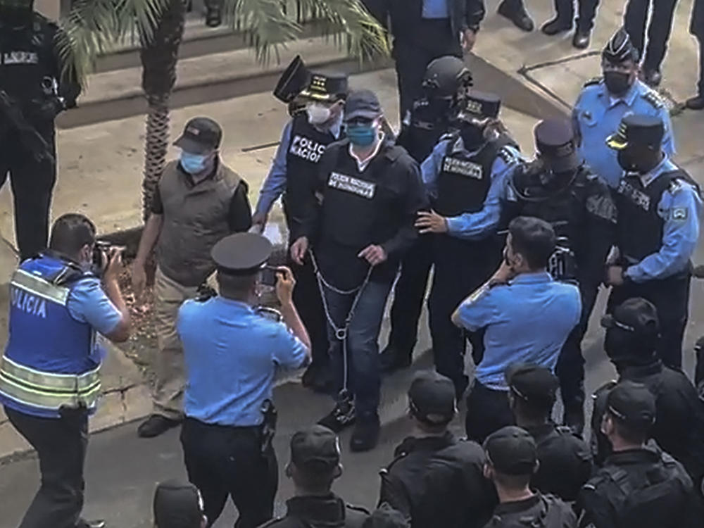 Police escort former Honduran President Juan Orlando Hernández, in handcuffs, from his house in Tegucigalpa after receiving an extradition order from the United States.