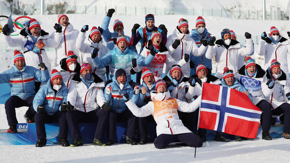 Gold medallists Tarjei Boe, Sturla Holm Laegreid, Johannes Thingnes Boe and Vetle Sjaastad Christiansen of Team Norway celebrate with their team and staff during Men's Biathlon 4x7.5km Relay flower ceremony on February 15, 2022 at the Beijing Winter Olympics.