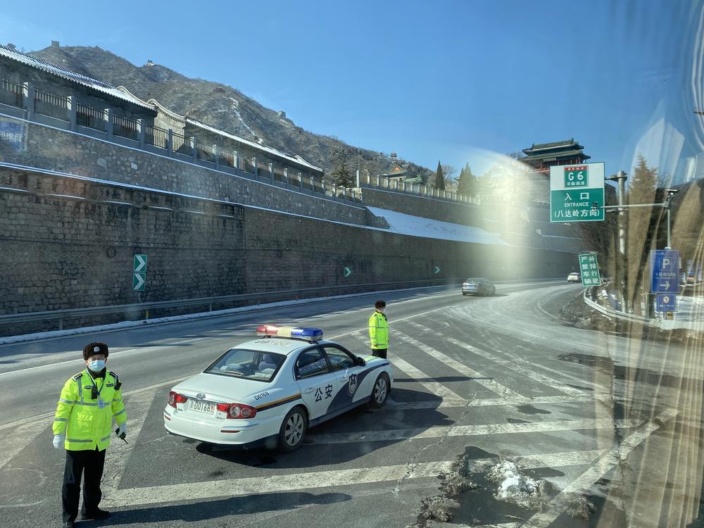 Police in China block off a part of the road for a tour bus leaving the 2022 Olympic bubble to pass through.