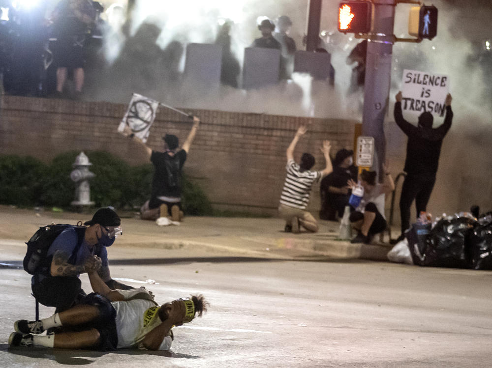 People help a protester after he was shot with a rubber bullet in Austin, Texas, in May 2020 while protesting the death of George Floyd. The Austin City Council on Thursday approved paying a combined $10 million to two people injured when officers fired beanbag rounds into crowds during the protests, including a college student who suffered brain damage.