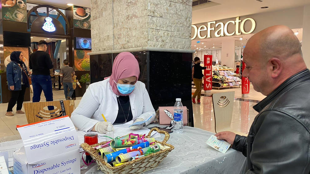 A health worker from the Baghdad Health Directorate fills out paperwork at a mobile COVID vaccine clinic in the Zayoona shopping mall in downtown Baghdad.