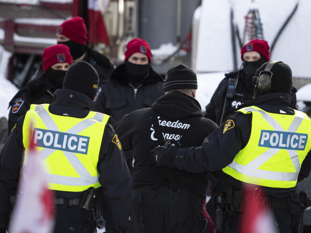 A man is led away after leaving his truck on Friday as police make arrests to end the ongoing protest in Ottawa.
