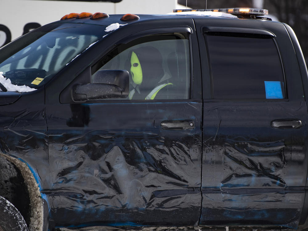 A tow operator wears a ski mask to hide their identity as they drive their truck with its company name concealed on Friday while assisting police in towing vehicles from the Ottawa protest.
