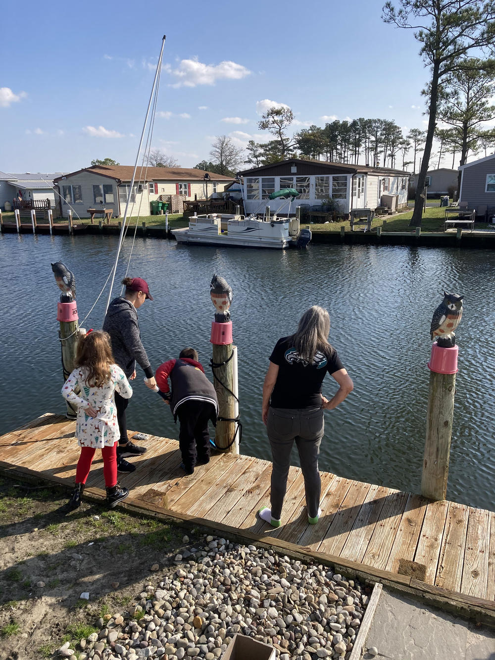 DeFrance on the dock outside her house in the mobile home park, with her daughter-in-law and grandkids.