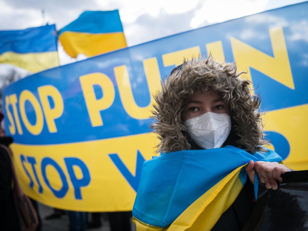 A protester stands in front of a banner reading 