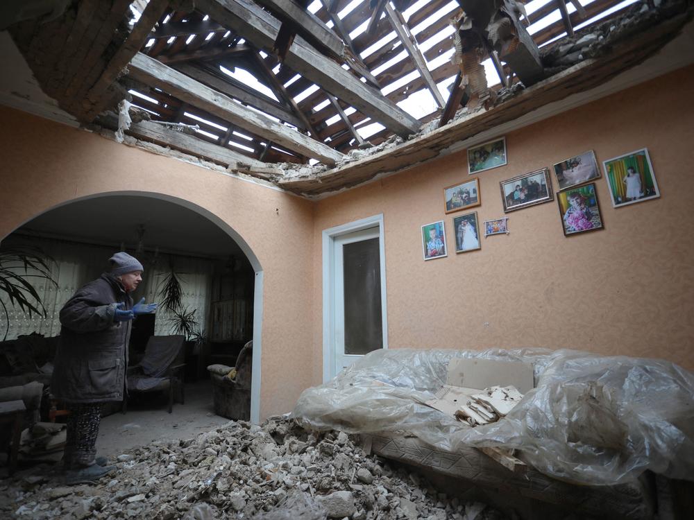 A local resident of the Ukrainian-controlled village of Stanytsia Luhanska, Luhansk region, gestures as she cleans up debris from her home after the shelling by Russia-backed separatists on February 18, 2022.