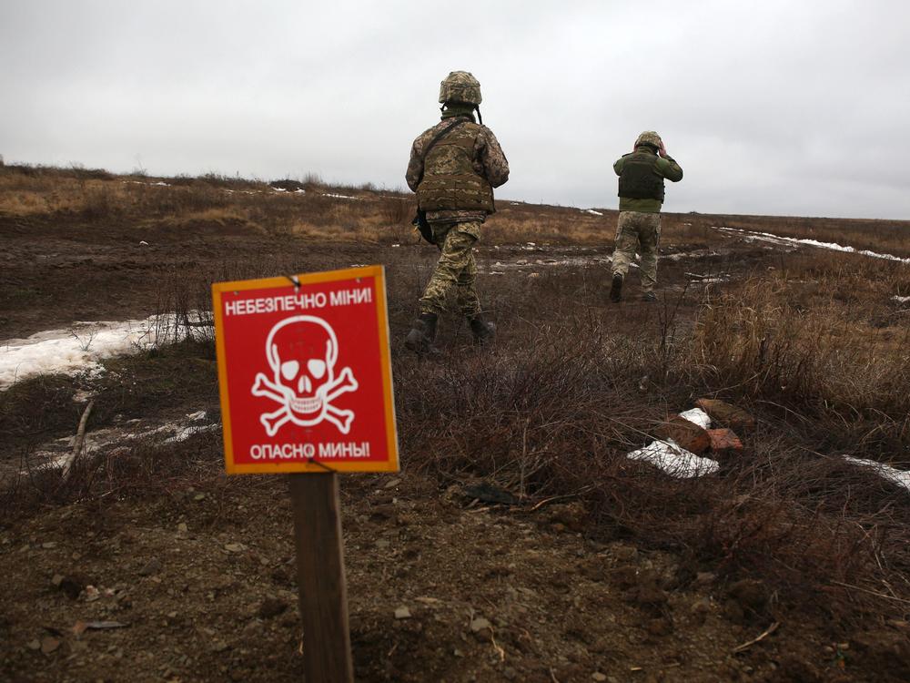 Ukrainian Military Forces servicemen walk past a metal plate that reads 