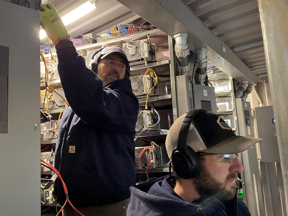 Workers install cryptocurrency mining computers inside a converted shipping container at the Compute North facility in Nebraska.