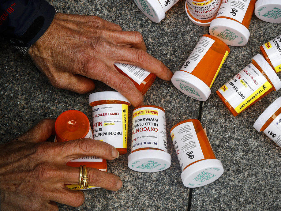 A protester gathers containers that look like OxyContin bottles at an anti-opioid demonstration in front of the U.S. Department of Health and Human Services headquarters in Washington, D.C., in 2019.