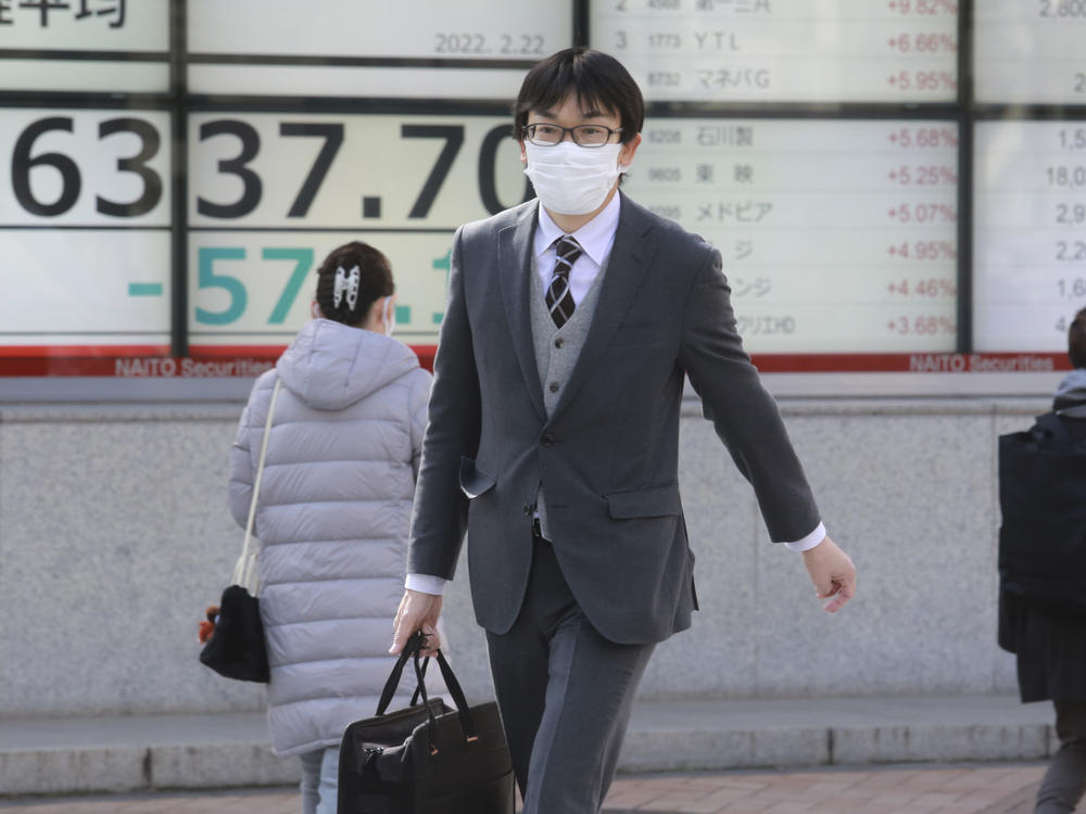 People walk by an electronic stock board of a securities firm in Tokyo on Tuesday. Shares fell sharply in Asia after Russian President Vladimir Putin ordered troops into separatist regions of eastern Ukraine.