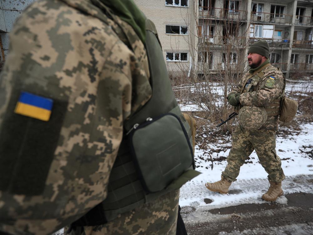 Ukrainian military forces walk in front of damaged buildings on the front line with Russia-backed separatists in Mariinka in the Donetsk region on Feb. 7.