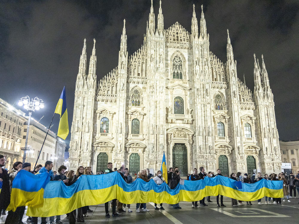 People hold a large flag of Ukraine in Duomo Square, Milan, Italy on Thursday.