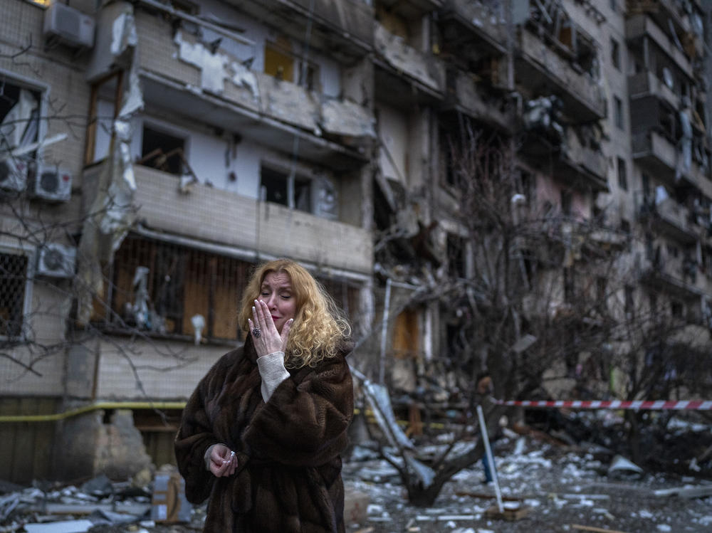 Natali Sevriukova reacts next to her house following a rocket attack the city of Kyiv, Ukraine, Friday, Feb. 25, 2022.