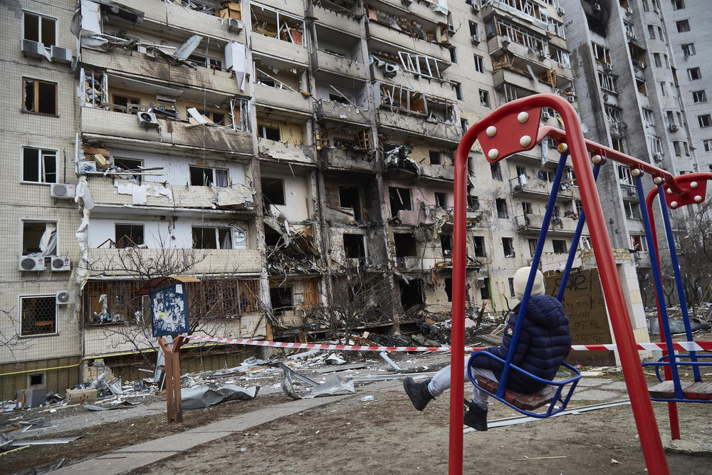 A child on a swing outside a residential building damaged by a missile on February 25, 2022 in Kyiv, Ukraine.